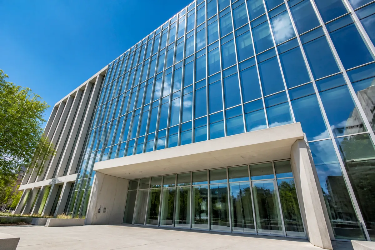 Façade contemporaine d&rsquo;un bâtiment institutionnel en verre, ciel dégagé